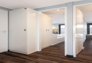 Interni moderni della houseboat Elysium nei Paesi Bassi con corridoio, porte bianche e pavimento in legno.