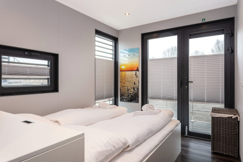 Camera da letto sulla houseboat “Elysium” nei Paesi Bassi con letto matrimoniale, ampie finestre e arredo moderno.