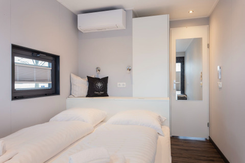 Camera moderna sulla houseboat «Elysium» nei Paesi Bassi con letto matrimoniale, finestra e stile minimalista.