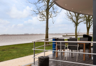 Blick von Hausboot «Elysium» in den Niederlanden mit Terrasse, Stühlen, Tisch und Fluss im Hintergrund.