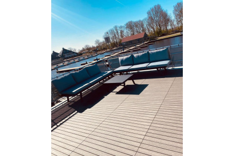 Sonnendeck des Hausboots 'Elysium' in den Niederlanden mit modernen Sofas und Blick aufs Wasser.
