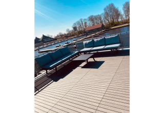 Terraza en la casa flotante 'Elysium' en los Países Bajos con sofás azules y vista al canal.