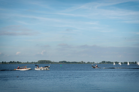 Vista dalla houseboat Elysium nei Paesi Bassi con barche a motore e a vela su un lago calmo.