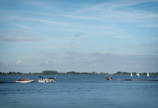 Blick vom Hausboot Elysium in den Niederlanden auf Boote und Segelschiffe auf einem ruhigen See.