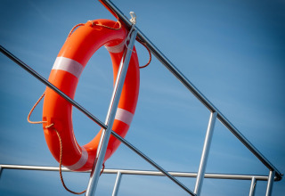 Rettungsring an der Reling des Hausboots «Elysium» in den Niederlanden vor blauem Himmel befestigt.