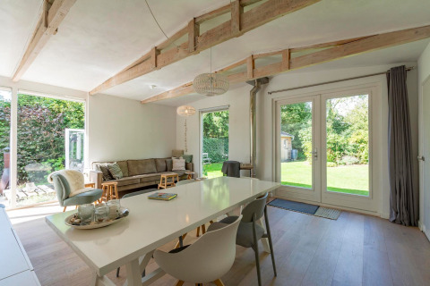 Lyst og moderne opholdsområde i lodge Eureka 109 i Holland med store vinduer ud til en grøn have.