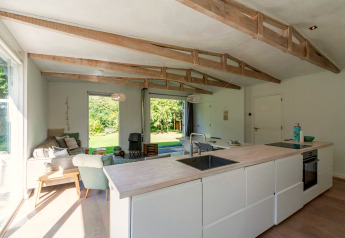 Intérieur moderne et lumineux de la lodge Eureka 109 aux Pays-Bas avec poutres apparentes et coin salon cosy.