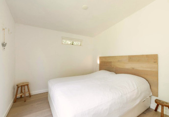 Chambre à la lodge Eureka 109 aux Pays-Bas, avec décoration minimaliste, linge blanc et tête de lit en bois.