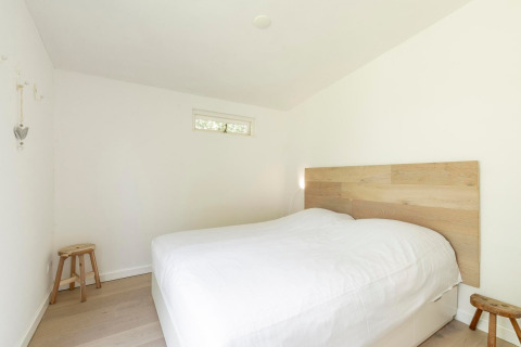 Soveværelse på lodge Eureka 109 i Holland med minimalistisk design, hvidt sengetøj og træhovedgærde.