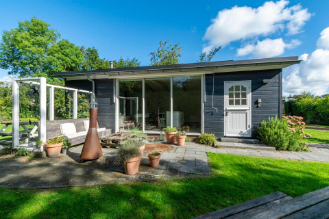 Moderne lodge ved navn Eureka 109 i Holland med stor have, terrasse, potteplanter og udendørs bænk.