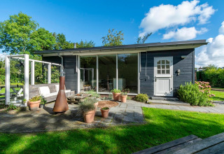 Moderne lodge ved navn Eureka 109 i Holland med stor have, terrasse, potteplanter og udendørs bænk.