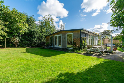 Hyggelig lodge Eureka 109 i Holland med moderne trædesign, stor græsplæne og udendørs siddeplads.