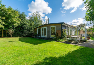 Hyggelig lodge Eureka 109 i Holland med moderne trædesign, stor græsplæne og udendørs siddeplads.