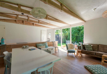 Salon moderne et lumineux à l'intérieur de la lodge Eureka 109 aux Pays-Bas, avec vue sur le jardin.