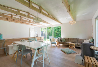 Lyst, moderne opholdsområde i lodge Eureka 109, Holland, med store vinduer og træloftsbjælker.