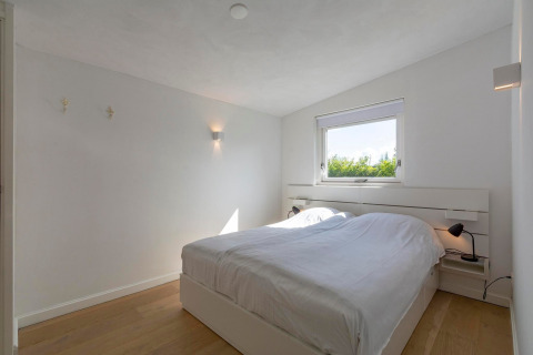 Lyst, minimalistisk soveværelse i Eureka 109-lodgen, Holland, med dobbeltseng og moderne indretning.
