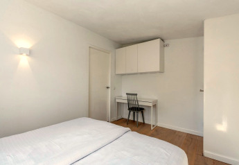 Chambre du lodge Eureka 109 aux Pays-Bas avec lit, bureau, chaise et placards blancs au mur.