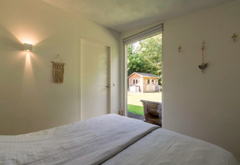 Chambre de la lodge Eureka 109 aux Pays-Bas, vue sur le jardin et un abri de jardin en bois.