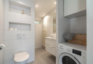 Moderne badeværelse med vaskemaskine, toilet, håndvask og indbyggede hylder på Eureka 109, Holland.