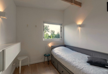 Chambre simple minimaliste au lodge Eureka 109 aux Pays-Bas, avec lit, fenêtre et décor épuré