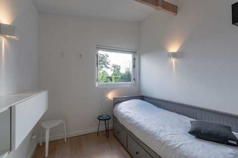 Minimalistisk enkeltværelse på Eureka 109 lodge i Holland, med enkeltseng, vindue og naturligt lys