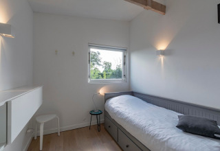 Minimalistisk enkeltværelse på Eureka 109 lodge i Holland, med enkeltseng, vindue og naturligt lys