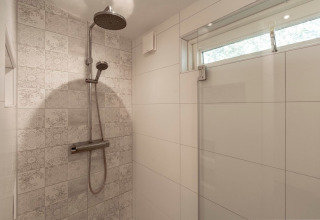 Moderne bruser i lodge Eureka 109 med mønstrede fliser og regnbruser, beliggende i Holland.