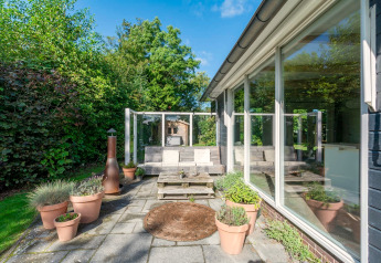 Terrasse ensoleillée du lodge Eureka 109 aux Pays-Bas, avec des plantes en pots et des sièges confortables.