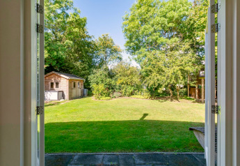Vue depuis une porte ouverte sur un jardin vert, un abri de jardin et des arbres à Eureka 109, Pays-Bas.