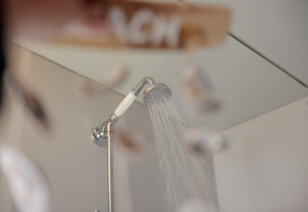 Pomme de douche avec de l'eau qui coule dans Tipitent de Jutter, tente tipi chaleureuse aux Pays-Bas.