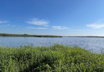 Udsigt over fredelig sø med grønne græsarealer og blå himmel ved Tipitent de Jutter i Holland.
