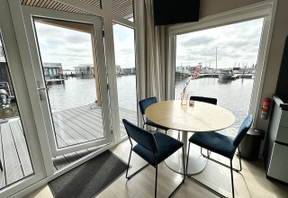 Indendørs spiseplads med udsigt over vandet fra husbåden RiggelBrug Sneekermeer i Holland.