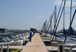 Både ligger fortøjet ved en gangbro ved husbåden RiggelBrug Sneekermeer i Nederlandene på en solskinsdag.