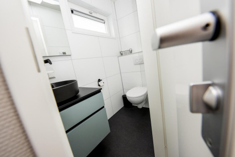 Moderne badeværelse med sort håndvask, ophængt toilet og vindue, taget ombord på husbåden RiggelBrug Sneekermeer i Holland.
