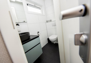 Moderne badeværelse med sort håndvask, ophængt toilet og vindue, taget ombord på husbåden RiggelBrug Sneekermeer i Holland.