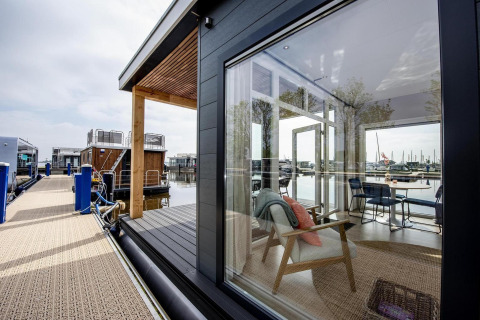 Husbaad ved kajen med store vinduer, udsigt over vandet og moderne interiør ved RiggelBrug Sneekermeer.
