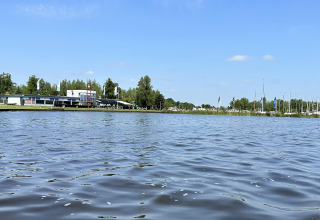Udsigt over vandet ved RiggelBrug Sneekermeer husbåd i Holland med bygning og både i baggrunden.