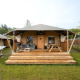 Safari telt Villatent Cottage med træterrasse, havemøbler og hængekøje på en grønt område i naturen.