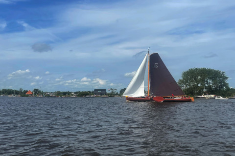 Udsigt over vandet ved Sneekermeer, med en sejlbåd og husbåde i baggrunden i Nederlandene.