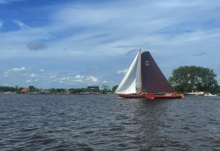 Udsigt over vandet ved Sneekermeer, med en sejlbåd og husbåde i baggrunden i Nederlandene.