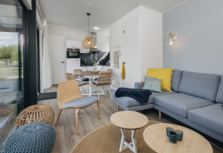 Moderne lodgeinteriør med lyst træ, blå sofa og spiseplads ved Park Wijdenes 4 i Holland.