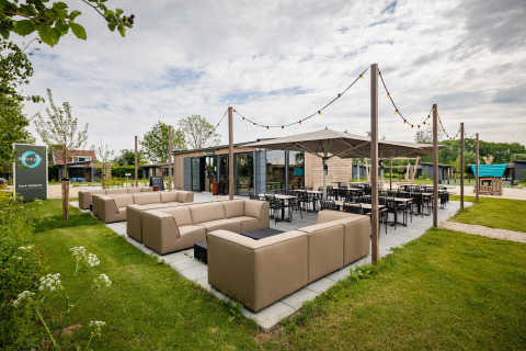 Udendørs opholdsområde ved Park Wijdenes 4 i Holland med moderne sofaer, stole og hyggelig belysning.