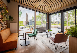 Moderne lodge lounge med store vinduer, komfortable siddepladser og udsigt over en udendørs terrasse.