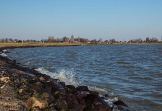 Billede af en kystnær lodge med stenstrand, bølger og udsigt til en landsby med en kirke i baggrunden.