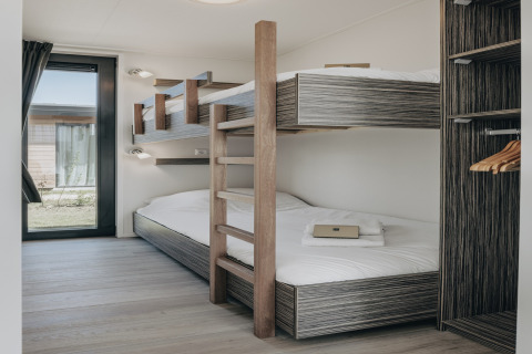 Moderne lodgeværelse med køjesenge, store vinduer og indbygget garderobe i Park Wijdenes 3, Holland.