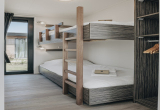 Moderne lodgeværelse med køjesenge, store vinduer og indbygget garderobe i Park Wijdenes 3, Holland.