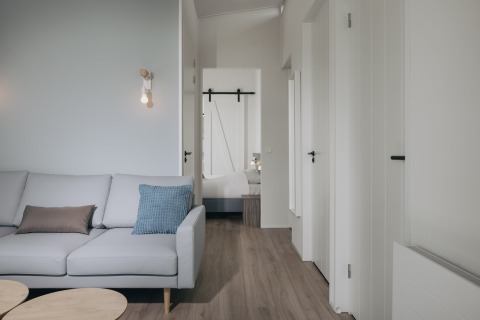 Moderne stue i Park Wijdenes 3, Holland, med lys sofa, træbord og adgang til soveværelse.