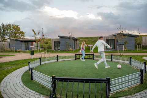 To personer spiller fodbold på et lille område foran moderne lodges i Park Wijdenes 3, Holland.