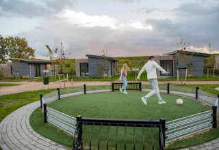 To personer spiller fodbold på et lille område foran moderne lodges i Park Wijdenes 3, Holland.