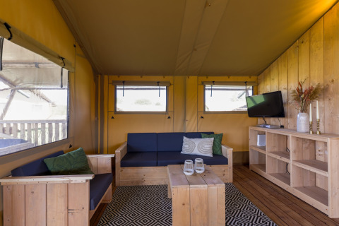Cozy safari tent interior at Villa Holiday Park IJsselhof 12, Netherlands, with wooden furniture and TV.